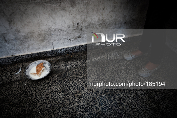 A girl standing next to a tin plate with food at a make-shift refugee camp in Jabalya, Gaza on July 18th, 2014. The former school currently...