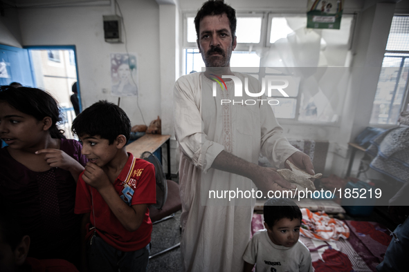 A man showing the little food he has left for his family in a make-shift refugee camp in Jabalya, Gaza on July 18th, 2014. The former school...