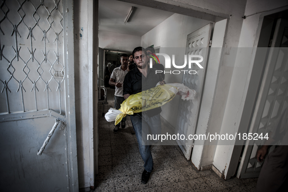 A man carries the dead bodies of a child that died during Israeli tank shells in the morning hours out of the Central Morgue of Gaza City on...