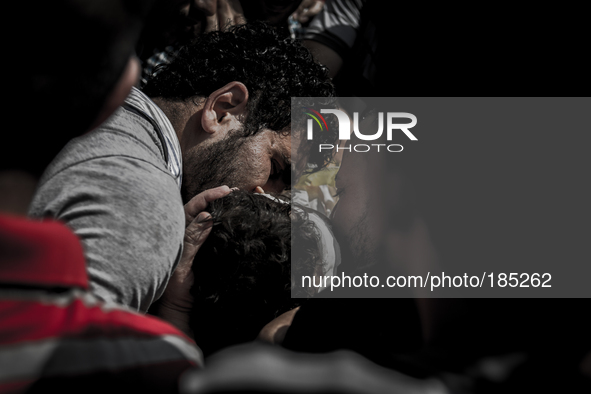 A man kisses the dead body of a young boy (5 years) at a funeral. The child was killed by a tank shell in Gaza City on July 20th, 2014.