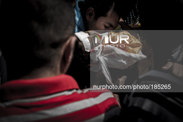 A man kisses the dead body of a young boy (5 years) at a funeral. The child was killed by a tank shell in Gaza City on July 20th, 2014.