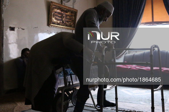 Syrian Umm Mohammed, helps her war injured husband exercise at their home in the rebel-held town of Douma, on the outskirts of the capital D...