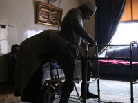 Syrian Umm Mohammed, helps her war injured husband exercise at their home in the rebel-held town of Douma, on the outskirts of the capital D...
