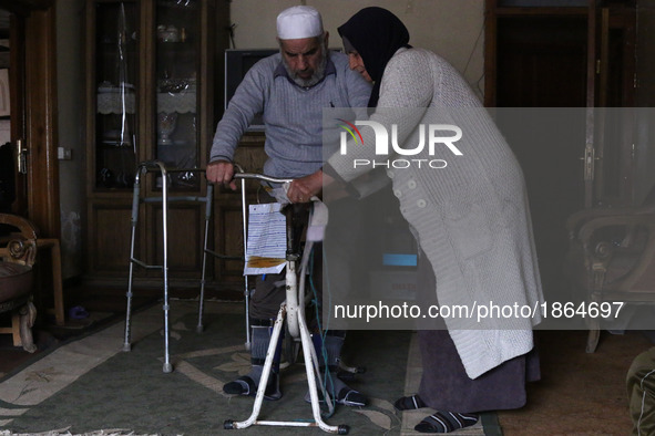 Syrian Umm Mohammed, helps her war injured husband exercise at their home in the rebel-held town of Douma, on the outskirts of the capital D...