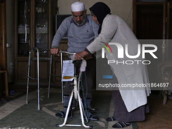 Syrian Umm Mohammed, helps her war injured husband exercise at their home in the rebel-held town of Douma, on the outskirts of the capital D...