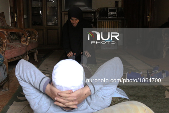 Syrian Umm Mohammed, performs rehabilitation exercises with her war injured husband at their home in the rebel-held town of Douma, on the ou...