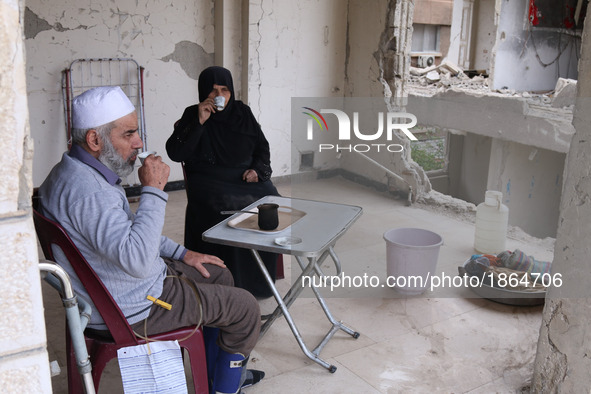 Syrian Umm Mohammed, and her husband drink coffee at their destroyed home in the rebel-held town of Douma, on the outskirts of the capital D...