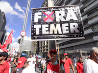 A demonstrator holds up a sign that reads 'Out Temer' during a workers union protest against President Michel Temer's government on Labor Da...