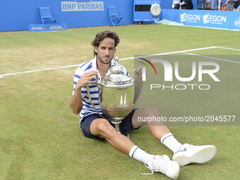 Feliciano Lopez of Spain seats on the grass while celebrates with the Trophy, after his victory against Marin Cilic of Croatia in their Men'...