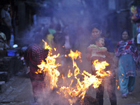 Nepalese devotee swing their child over the burning straw effigy of the demon Ghantakarna during the Gathemangal festival celebrated at Bhak...
