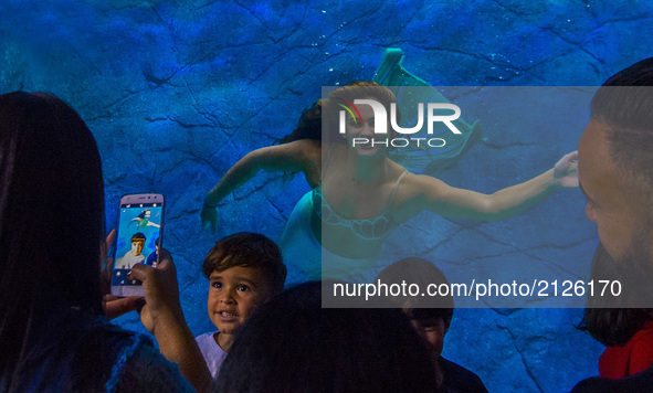 Visitors watch several mermaids while they swim in a giant tank during a show at an aquarium in Sao Paulo, Brazil, on August 14, 2017. 