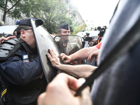 Metalworkers face off with police officers as they march with banners and flags in the streets of Paris on October 13, 2017. Several thousan...