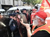 Metalworkers face off with police officers as they march with banners and flags in the streets of Paris on October 13, 2017. Several thousan...