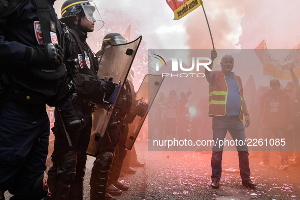 Metalworkers and police officers are surrounded by smoke as they march with banners and flags in the streets of Paris on October 13, 2017. S...