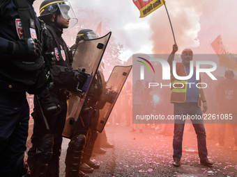 Metalworkers and police officers are surrounded by smoke as they march with banners and flags in the streets of Paris on October 13, 2017. S...