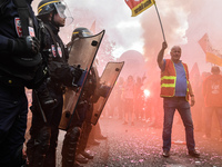 Metalworkers and police officers are surrounded by smoke as they march with banners and flags in the streets of Paris on October 13, 2017. S...