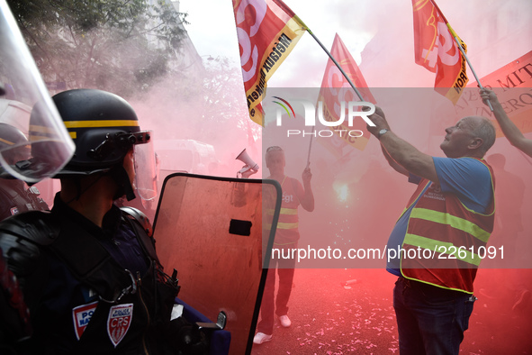 Metalworkers and police officers are surrounded by smoke as they march with banners and flags in the streets of Paris on October 13, 2017. S...