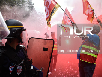 Metalworkers and police officers are surrounded by smoke as they march with banners and flags in the streets of Paris on October 13, 2017. S...