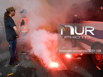 Metalworkers and police officers are surrounded by smoke as they march with banners and flags in the streets of Paris on October 13, 2017. S...