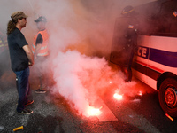 Metalworkers and police officers are surrounded by smoke as they march with banners and flags in the streets of Paris on October 13, 2017. S...