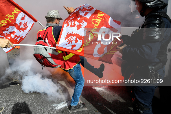 Metalworkers and police officers are surrounded by smoke as they march with banners and flags in the streets of Paris on October 13, 2017. S...