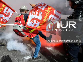 Metalworkers and police officers are surrounded by smoke as they march with banners and flags in the streets of Paris on October 13, 2017. S...