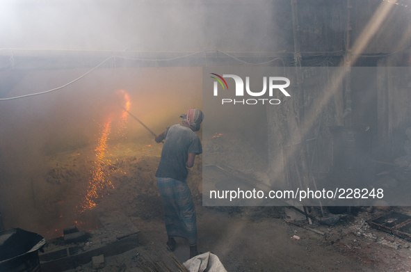 DHAKA, BANGLADESH. Juli  2013. Worker remove the lead slag with a scoop, without any safety protection. the lead dust is verry danger. The m...