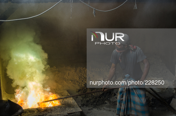 DHAKA, BANGLADESH. Juli  2013. Worker remove the lead slag with a scoop, without any safety protection. the lead dust is verry danger. The m...