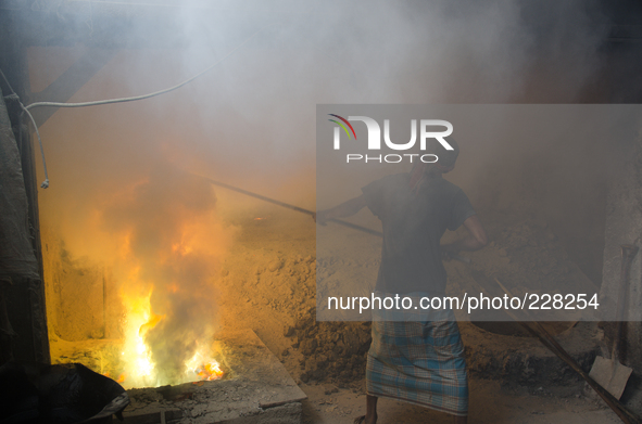 DHAKA, BANGLADESH. Juli  2013. Worker remove the lead slag with a scoop, without any safety protection. the lead dust is verry danger. The m...