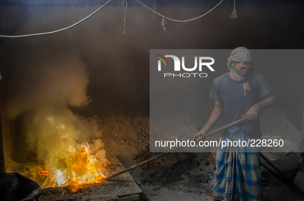 DHAKA, BANGLADESH. Juli  2013. Worker remove the lead slag with a scoop, without any safety protection. the lead dust is verry danger. The m...