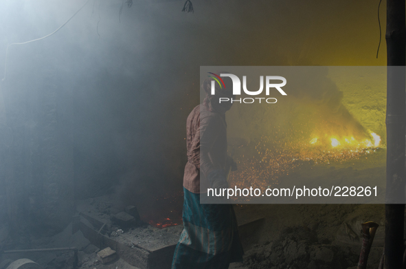 DHAKA, BANGLADESH. Juli  2013. Worker remove the lead slag with a scoop, without any safety protection. the lead dust is verry danger. The m...