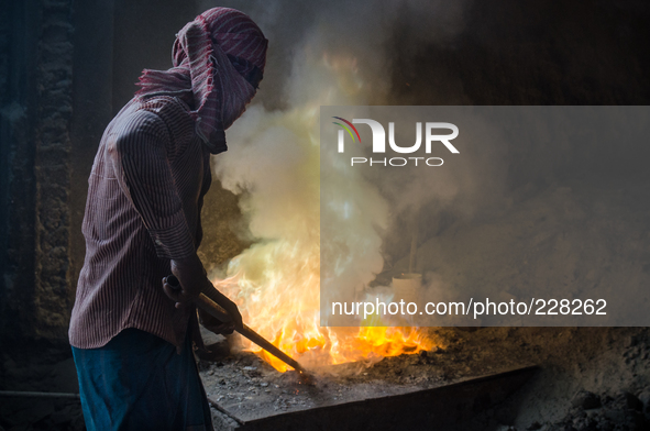 DHAKA, BANGLADESH. Juli  2013. Worker remove the lead slag with a scoop, without any safety protection. the lead dust is verry danger. The m...