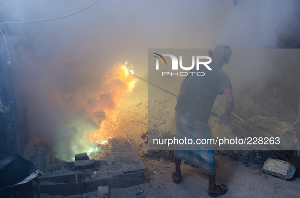 DHAKA, BANGLADESH. Juli  2013. Worker remove the lead slag with a scoop, without any safety protection. the lead dust is verry danger. The m...