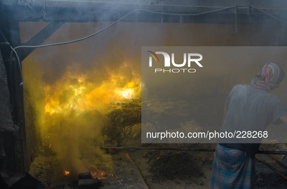 DHAKA, BANGLADESH. Juli  2013. Worker remove the lead slag with a scoop, without any safety protection. the lead dust is verry danger. The m...