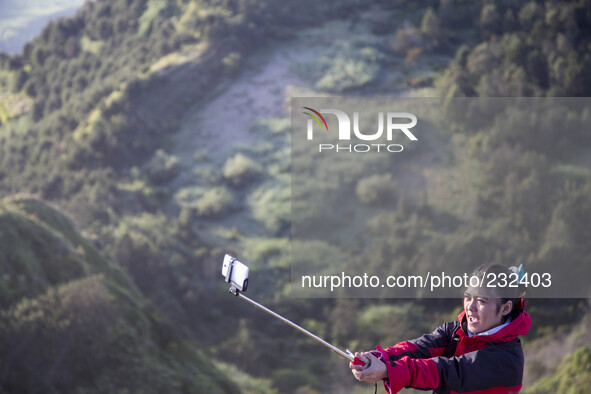 A girl doing selfie at the top of Sikunir Mountain in Dieng. Dieng plateau in Central Java, is part of the district of Banjarnegara and Wono...