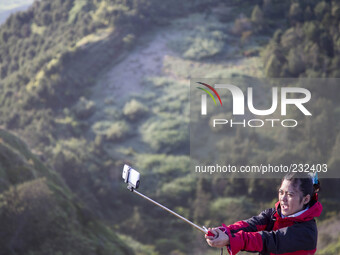 A girl doing selfie at the top of Sikunir Mountain in Dieng. Dieng plateau in Central Java, is part of the district of Banjarnegara and Wono...