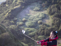 A girl doing selfie at the top of Sikunir Mountain in Dieng. Dieng plateau in Central Java, is part of the district of Banjarnegara and Wono...