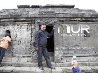 A visitor pose for a mobile phone photo at Temple Complex in Dieng. Dieng plateau in Central Java, is part of the district of Banjarnegara a...