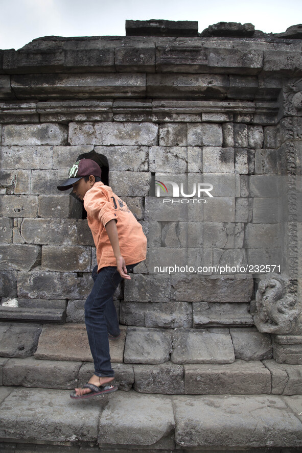 A child with his curiosity to see inside the temple at  Temple complex in Dieng. Dieng plateau in Central Java, is part of the district of B...