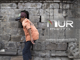 A child with his curiosity to see inside the temple at  Temple complex in Dieng. Dieng plateau in Central Java, is part of the district of B...