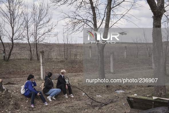 A group of women observes the passage of a military helicopter 