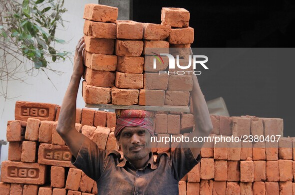 Indian Labour carries pile of bricks on his head near a construction site at Gurugram, Haryana on 16th December 2017. 