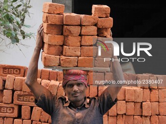 Indian Labour carries pile of bricks on his head near a construction site at Gurugram, Haryana on 16th December 2017. (