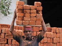 Indian Labour carries pile of bricks on his head near a construction site at Gurugram, Haryana on 16th December 2017. (