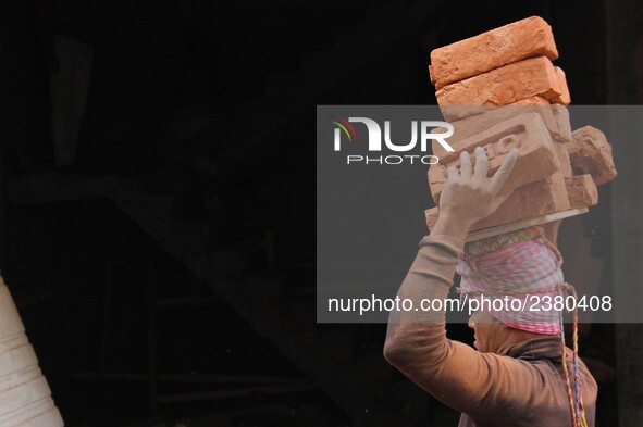 Indian Labour carries pile of bricks on his head near a construction site at Gurugram, Haryana on 16th December 2017. 