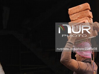 Indian Labour carries pile of bricks on his head near a construction site at Gurugram, Haryana on 16th December 2017. (