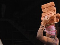 Indian Labour carries pile of bricks on his head near a construction site at Gurugram, Haryana on 16th December 2017. (