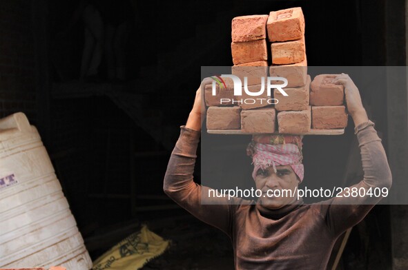 Indian Labour carries pile of bricks on his head near a construction site at Gurugram, Haryana on 16th December 2017. 