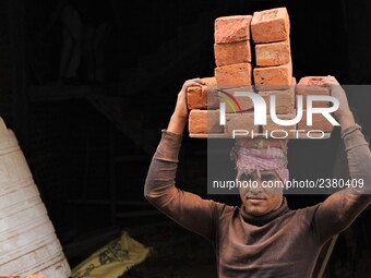 Indian Labour carries pile of bricks on his head near a construction site at Gurugram, Haryana on 16th December 2017. (