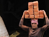 Indian Labour carries pile of bricks on his head near a construction site at Gurugram, Haryana on 16th December 2017. (